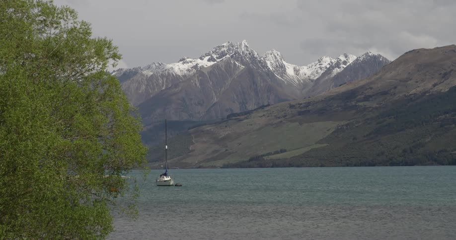 Boat sailing down a wide river with mountains in the background