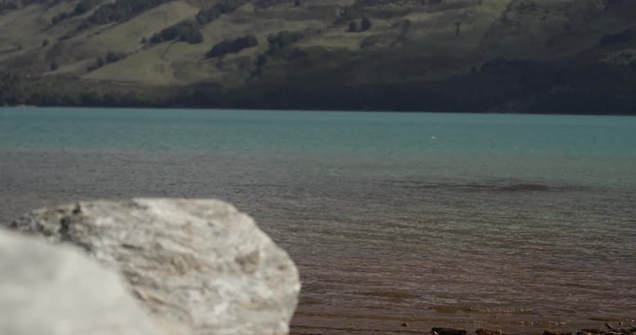 Water rippling towards a rocky shoreline with hills in the background
