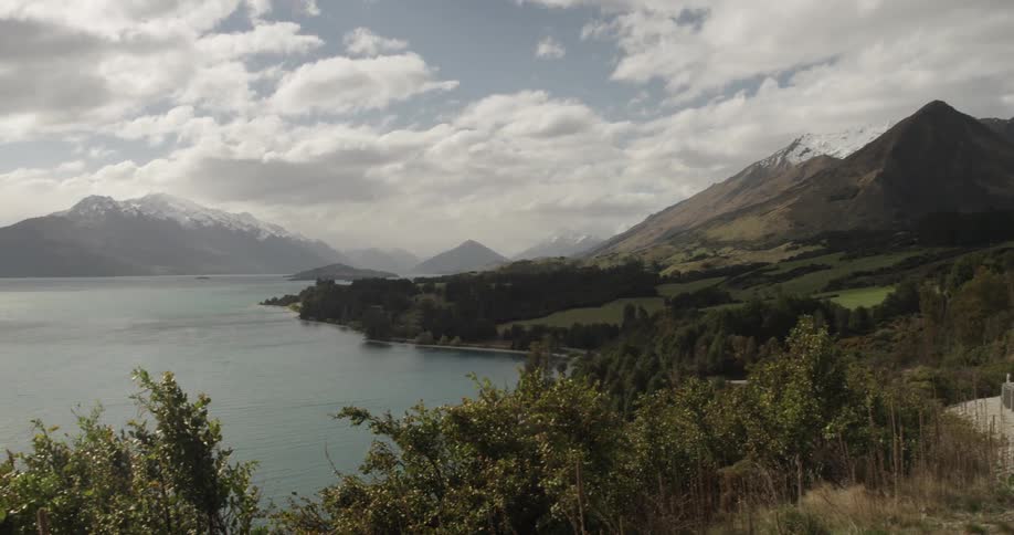 A view of a body of water surrounded by snow-capped mountains under a cloudy sky
