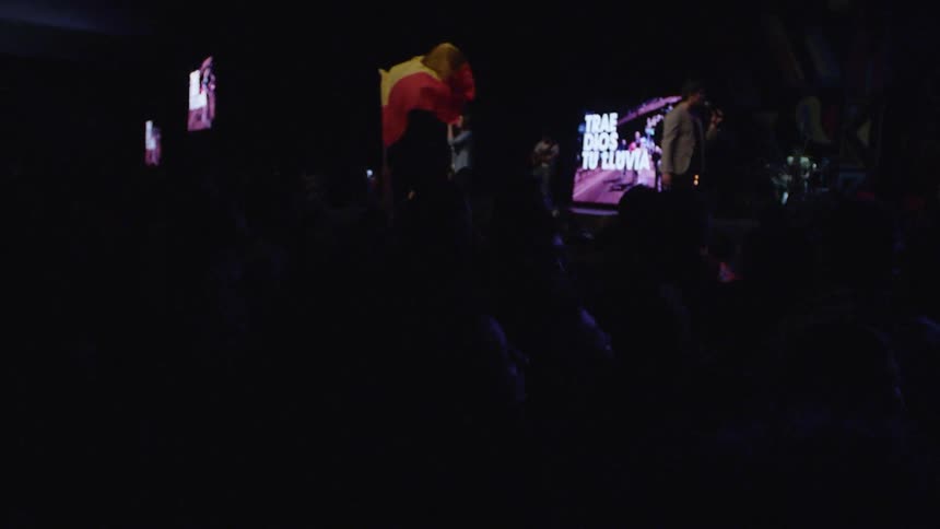 A band performs onstage while the audience jumps up and down