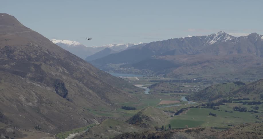A plane flying beside a mountain in a valley
