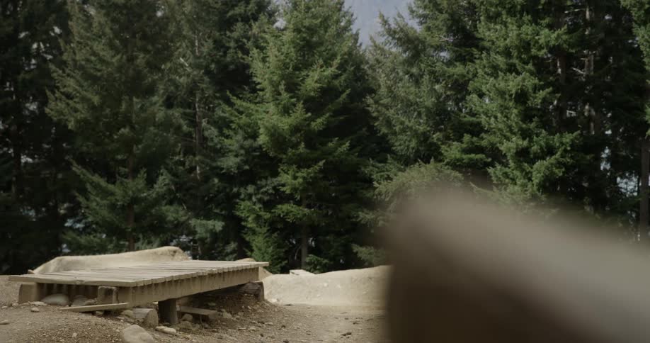 A young man riding a bike over a bridge on a dirt obstacle course