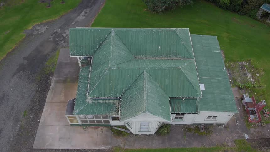 A very large estate house with a green roof is panned into view