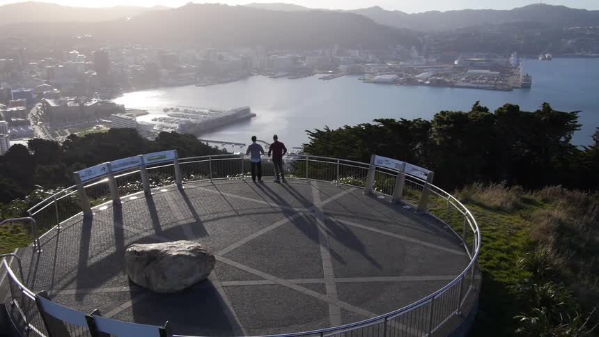 Couple standing inside a concrete circle overlooking a harbor and lake