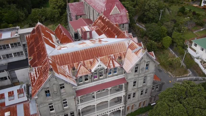 A bird's-eye-view of large building with a red roof that is surrounded by other buildings and a few homes