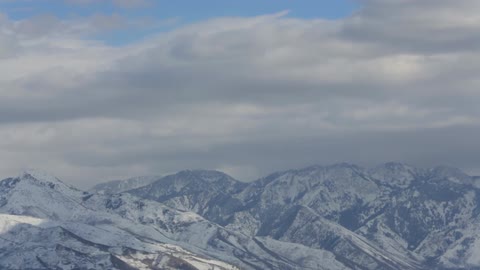 Clouds float over snow-covered mountains