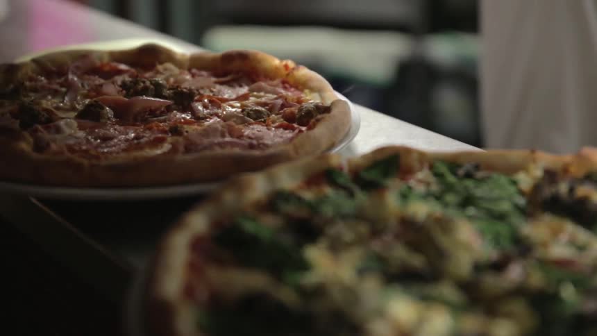 Hot, steaming pizzas sit in a restaurant kitchen