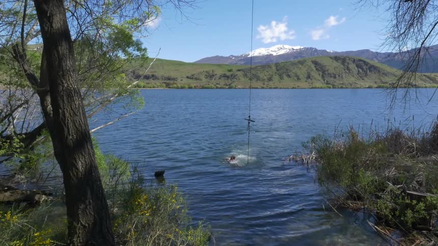 A person swims in a clear blue lake in the country
