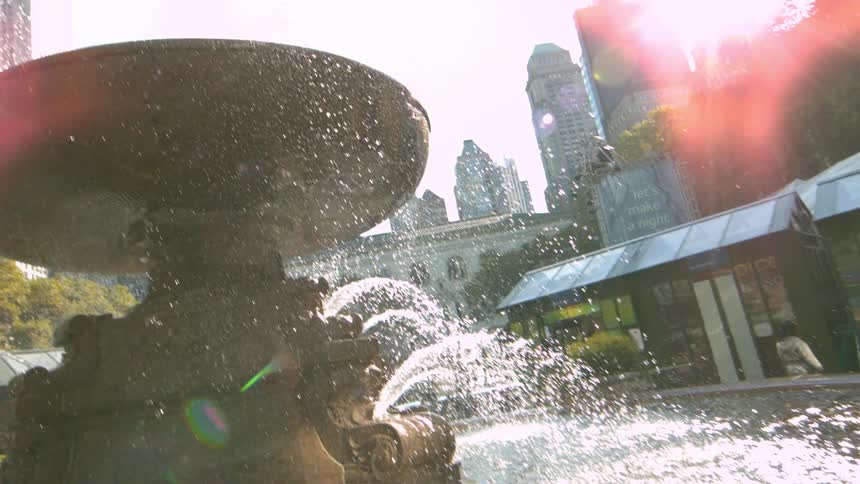 Water spraying from a fountain and splashing into a pool in an urban area on a sunny day