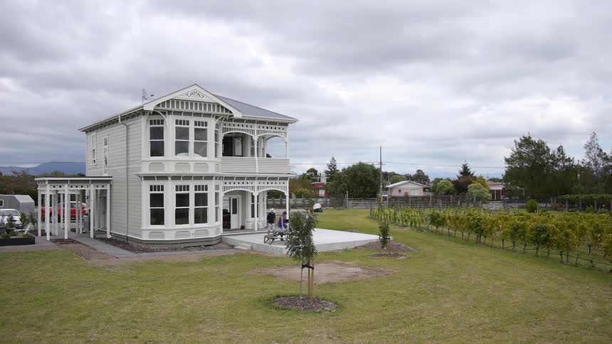 A vineyard surrounds a white colonial building