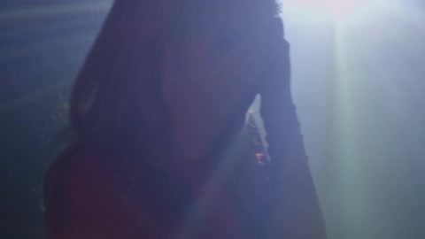 A woman spins in front of flashing lights