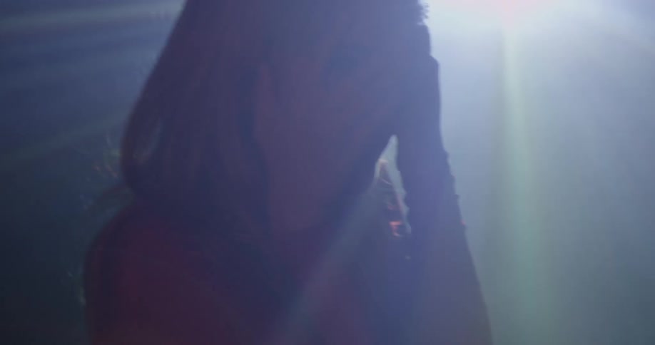A woman spins in front of flashing lights