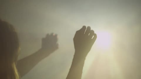 A woman is raising her hands towards a light