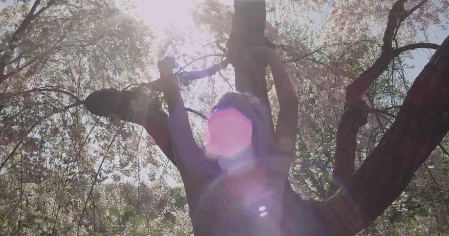A woman slowly spins around under the shade of a tree