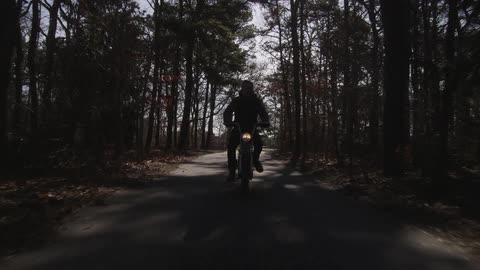 A motorcyclist bikes down a forest road