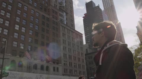 A man stands looking at a large building in a city