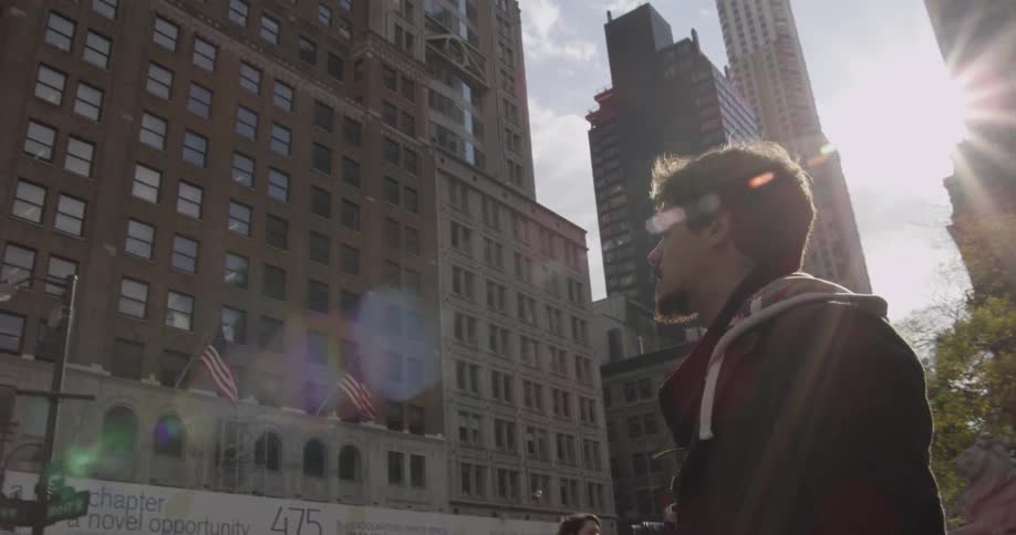 A man stands looking at a large building in a city