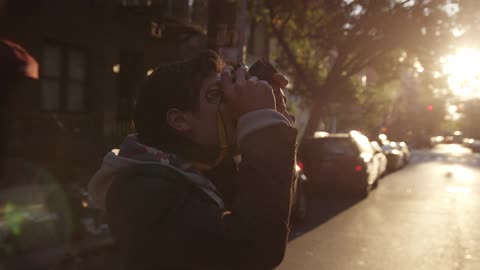 A man walks in a city street and snaps a photograph