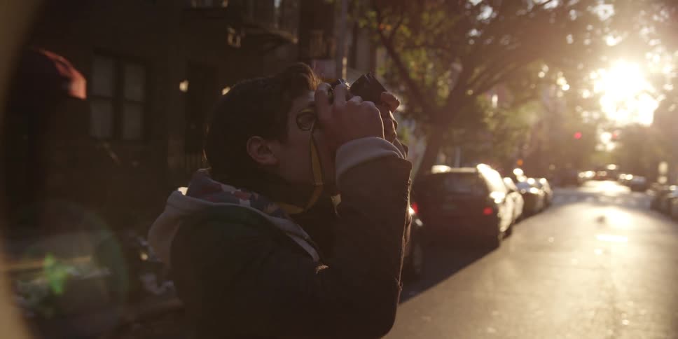 A man walks in a city street and snaps a photograph