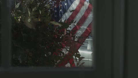 A flag and a car is seen through a window
