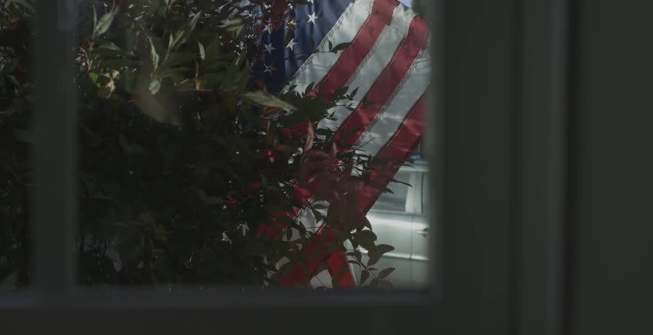 A flag and a car is seen through a window
