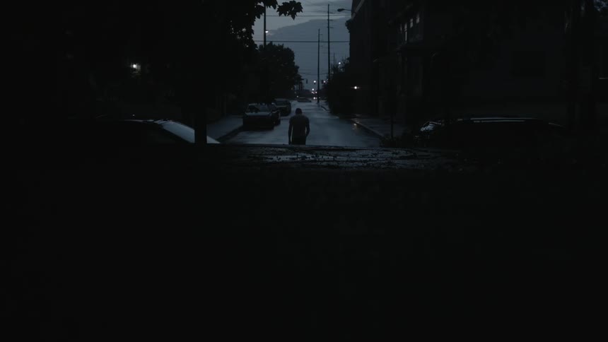 A man walks down a city street at night