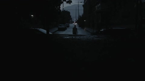 A person walks down a dark street at dusk