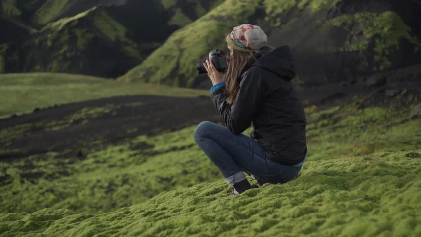 A woman takes a photograph in the wilderness