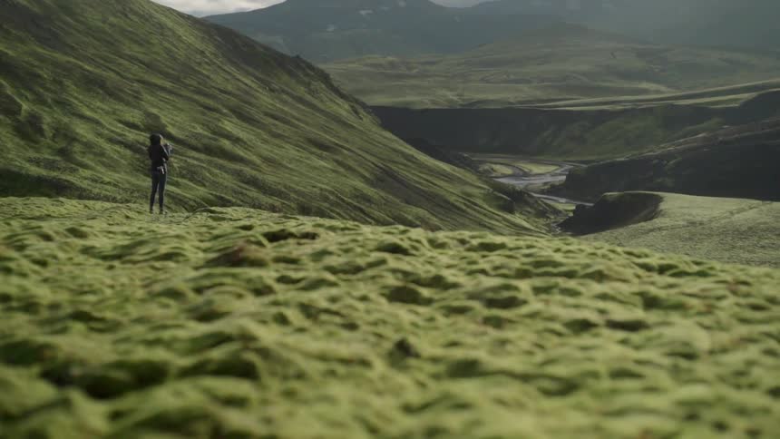 A woman taking a picture from atop of a hill