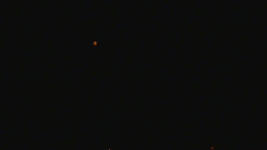 Sparks float upward through blackness
