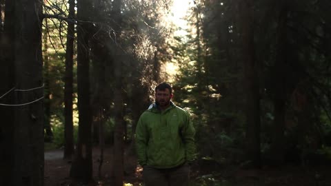 Standing man drinking a warm cup of coffee with others in the wilderness