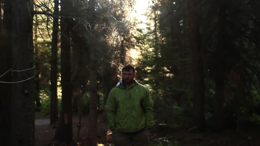 Standing man drinking a warm cup of coffee with others in the wilderness