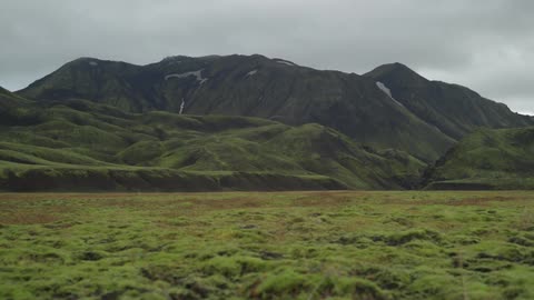 A green, hilly mountain looms in the distance