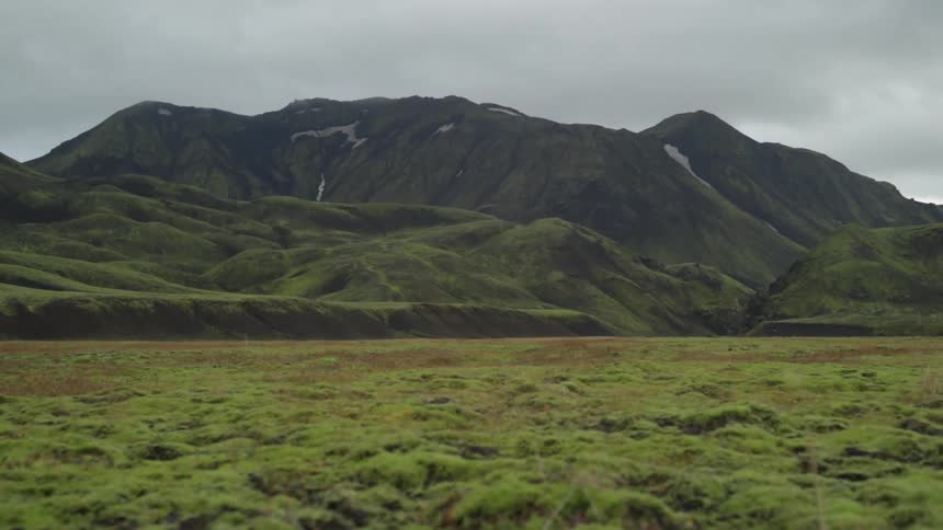 A green, hilly mountain looms in the distance