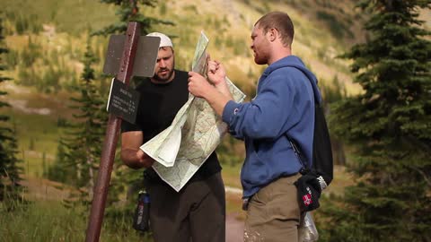 Two hikers consult a map in the woods