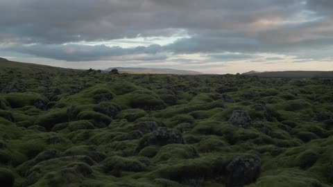 Grassy hills stretch into the distance with clouds floating overhead