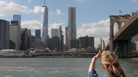 A woman looks over a river towards a city