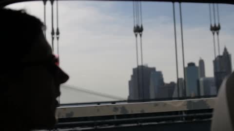 A man looks out over the city while crossing a bridge