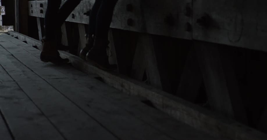Two females wearing tights and boots stepping onto the bottom board of a railing