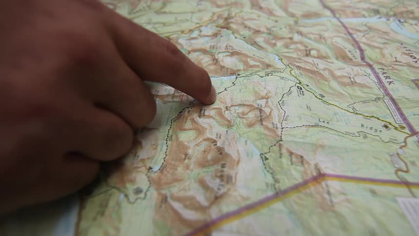 A person runs their finger along a road on a map
