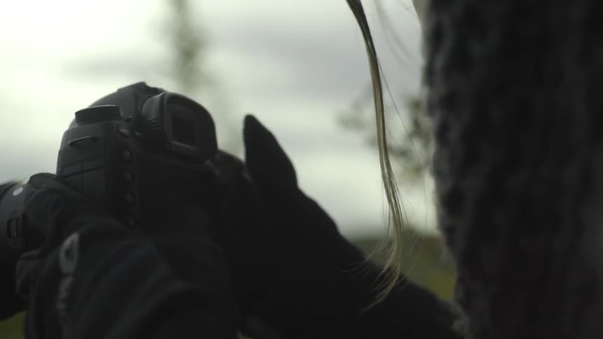 A woman adjusting her camera on a cold day