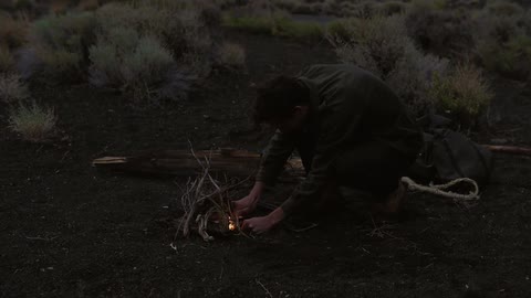 Man trying to start a fire outside on a cloudy night