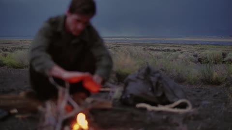 A man warming his hands with a campfire