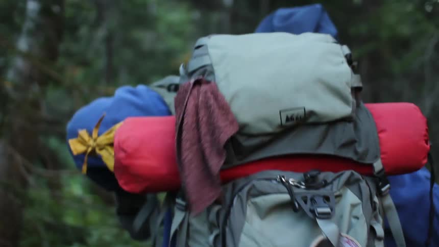 A person lifts a backpack onto their shoulders