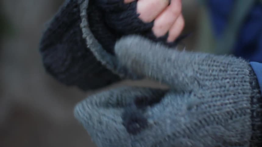 A person flips the tops of their gloves over their fingers
