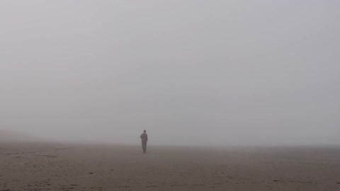 A man walks through a foggy desert