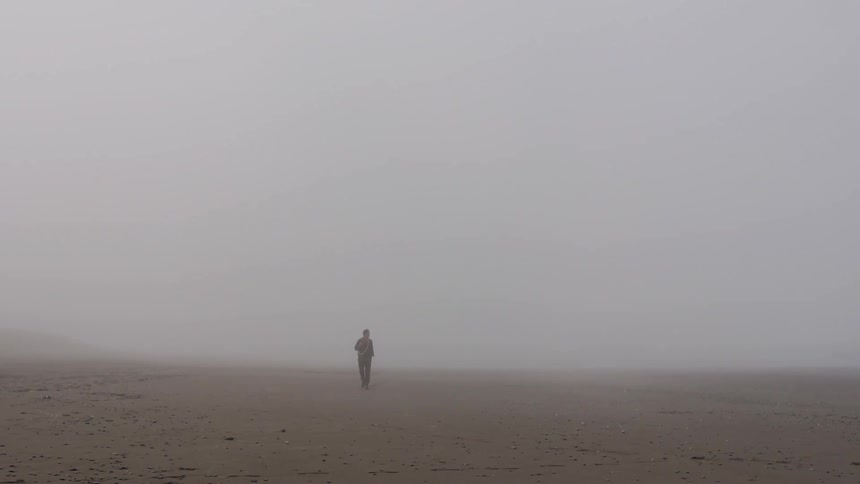 A man walks through a foggy desert