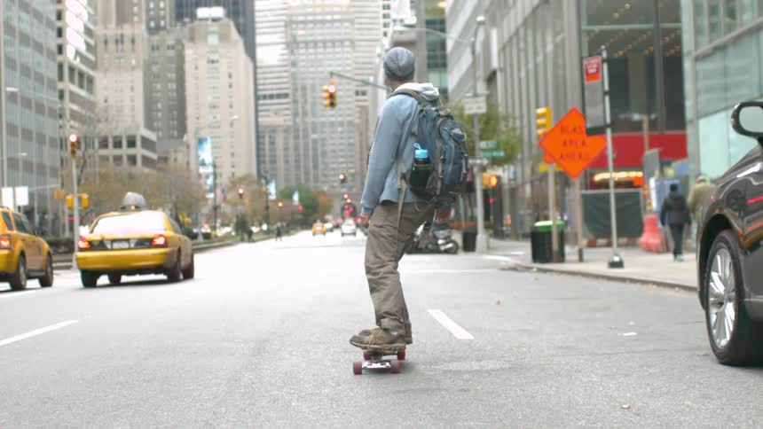 Man skateboards through a city street