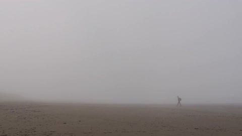 A man hikes through a foggy opening