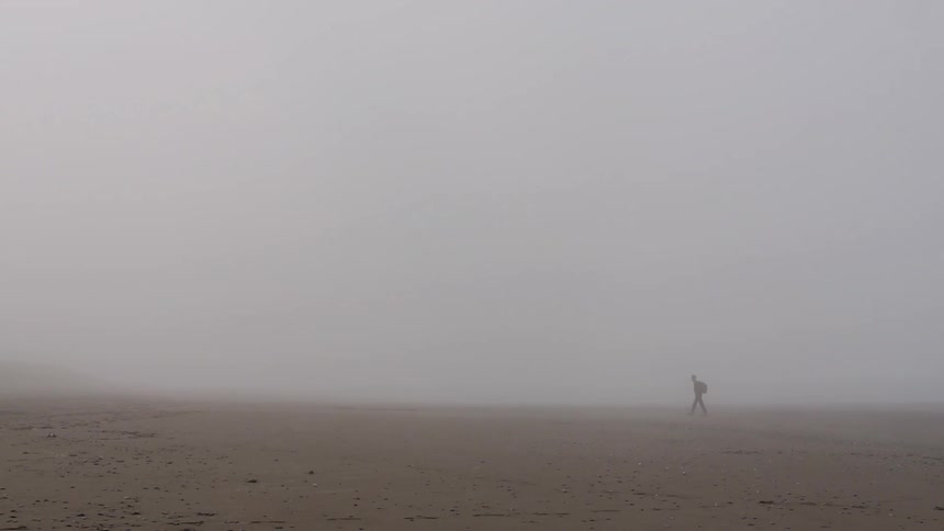 A man hikes through a foggy opening